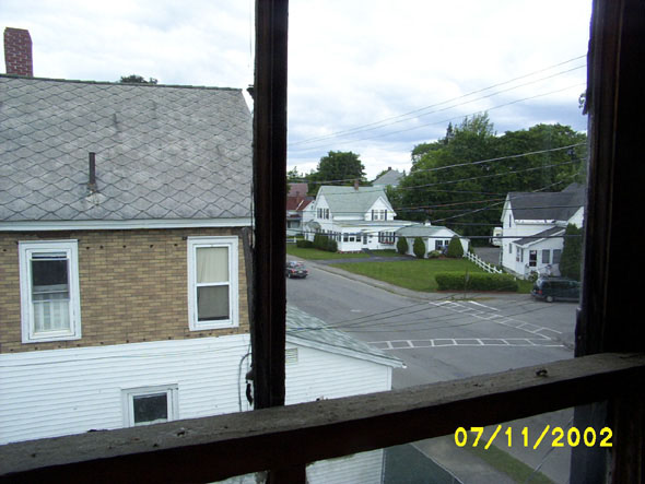 A view of the street through the only window, on the north end of the attic. I'll probably be replacing this window entirely when I put one in on the south side. We're hoping to be able to buy the white/brown house adjacent to our's.