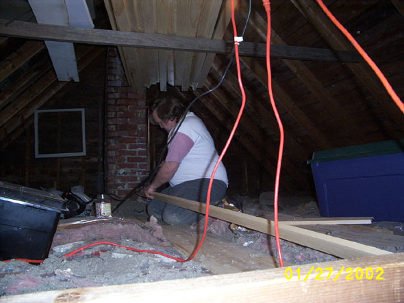 Kneeling on the very first few boards that I put down, that's me sawing on the end of one.  The view is looking north from the attic entryway.