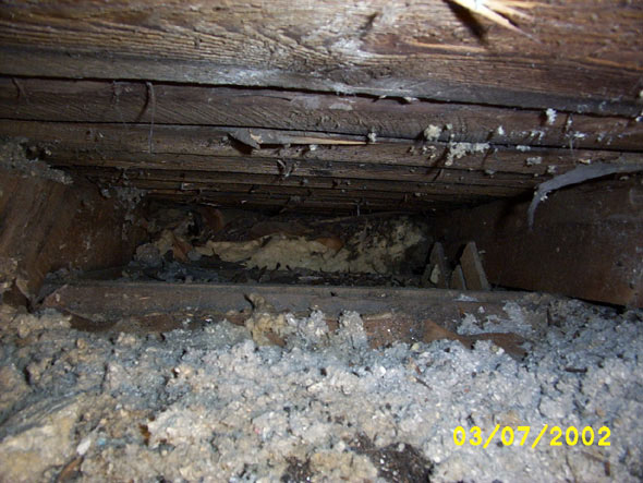 Where there is nothing blocking the eaves on the east side, it is insulated further than I can reach.  The insulation must have been inserted when the roof was put in place, or when it was replaced at some point.  I'm pulling up as much of it as I can, but I can't clear the passage all the way to the eave.