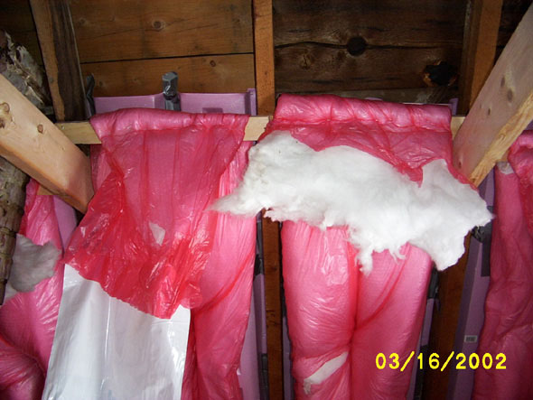 The upper end of each roll of insulation is stapled to the boards, and along the center.