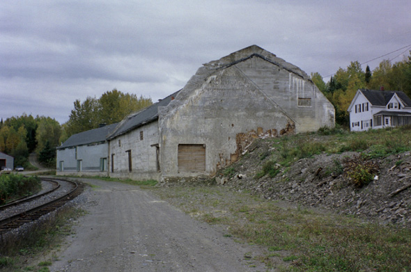 In the foreground, an old warehouse, as seen from the siding road adjacent to Pond View Road.